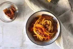 Un piatto invitante di bucatini all'amatriciana, con guanciale croccante e una salsa rossa saporita, spolverato di formaggio grattugiato.