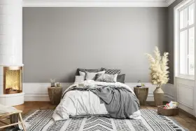 Dormitorio acogedor con chimenea encendida. El gris claro de la pared combina con blanco, negro y tonos tierra, creando un ambiente sereno.