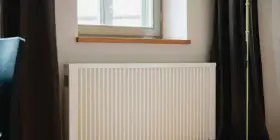 Radiateur électrique blanc sous une fenêtre, prêt pour un changement grâce à l'aide de l'état.