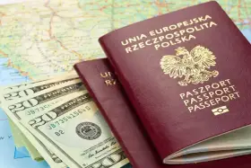 Dwa polskie paszporty i banknoty dolarowe na mapie. Planujesz podróż? Sprawdź, czy do Serbii potrzebny jest paszport.