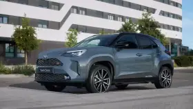 Szary Toyota Yaris Cross hybryda stoi na tle nowoczesnego budynku.