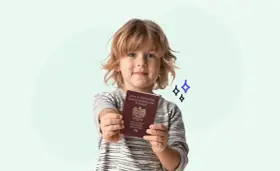 Uśmiechnięty chłopiec trzyma polski paszport. Teraz łatwo wyrobisz paszport dla dziecka online.