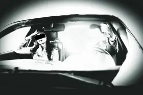 Frau im Auto, die sich die Hand ans Gesicht legt, während ein greller Blitz aufleuchtet. Ein blitzer foto, das die Szene einfängt.