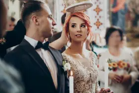 Para ślubna w kościele, z koroną nad głowami. Panna młoda w koronkowej sukni, pan młody w garniturze. W tle goście. Zastanawiasz się, jakie dokumenty do ślubu?