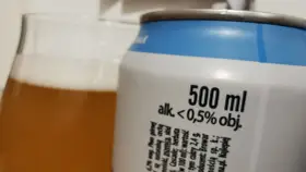 Szklanka piwa i puszka z informacją "alk. < 0,5% obj.". Zastanawiasz się, ile promili po jednym piwie? To piwo ma poniżej 0,5% alkoholu.