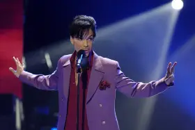 Prince w fioletowej marynarce śpiewa na scenie. Jego śmierć była szokiem dla fanów.