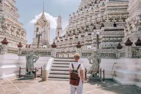 Młody turysta z plecakiem podziwia majestatyczną świątynię Wat Arun w Bangkoku. Czy Bangkok jest bezpieczny? Tak, zwłaszcza w takich pięknych i spokojnych miejscach.