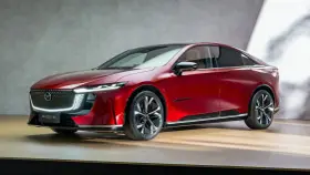 Elegancka, czerwona mazda elektryczna z nowoczesnym designem, prezentowana na drewnianej scenie.