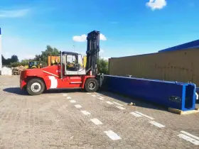 Czerwony wózek widłowy przygotowuje się do przeładunku długiego, niebieskiego elementu. To przykład sprawnego cross dockingu.