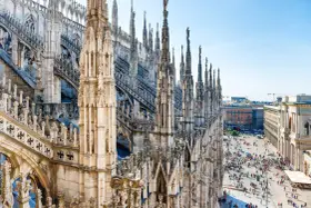 Majestatyczne iglice katedry Duomo w Mediolanie w listopadzie, z widokiem na tętniący życiem plac poniżej.