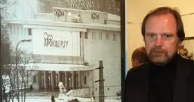 Mężczyzna z brodą obok plakatu kina "Moskwa" z napisem "Czas Apokalipsy".