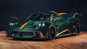 Pagani Huayra w kolorze głębokiej zieleni z pomarańczowymi akcentami, prezentuje swoje karbonowe nadwozie na drewnianej podłodze.