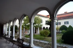 Portico con archi e colonne bianche, panchine e un giardino interno. Per sapere isola degli armeni come arrivare, visita questo luogo tranquillo.
