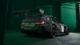 Wyścigowe BMW M3 2025 w kamuflażu, z ogromnym spojlerem i agresywnym dyfuzorem.