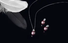 A delicate necklace and earrings featuring pink pearls, symbolizing love and purity. A white feather rests nearby, adding an ethereal touch.