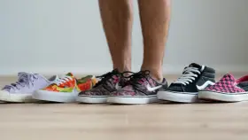 Un hombre elige entre varias zapatillas de **material canvas**. Hay modelos de colores, estampados florales, de cuadros y lisos.