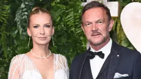 Cezary Pazura z żoną Edytą na ściance. Ona w białej, zdobionej sukni, on w eleganckim garniturze.