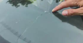 Palec wskazujący na pękniętej szybie samochodowej. Sprawdź autoglass cennik, aby poznać koszt naprawy.