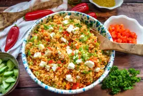 Frischer bulgursalat mit feta, Tomaten, Paprika und Frühlingszwiebeln, garniert mit Petersilie.