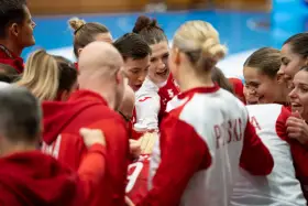 Drużyna piłki ręcznej w czerwonych strojach, zjednoczona przed meczem. Emocje i determinacja na twarzach zawodniczek podczas mistrzostw świata.