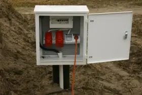 Skrzynka elektryczna z zabezpieczeniami i gniazdami, gotowa do tauron przyłączenie prądu do działki. Pomarańczowy kabel wpięty do gniazda.
