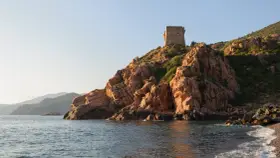 Wieża strażnicza na skalistym wybrzeżu, w oddali góry. Malownicza sceneria na corse wyspie.