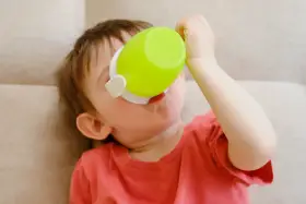 Małe dziecko pije z zielonego kubka niekapka LOVI.
