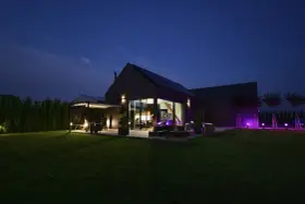Nowoczesny dom nocą, z oświetlonym ogrodem i tarasem. Analiza prawdziwych kosztów eksploatacji domów pasywnych w polskich warunkach klimatycznych.