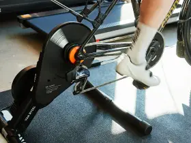 A cyclist's feet pedal on a bike connected to a magnetic resistance trainer, ready for an indoor workout.