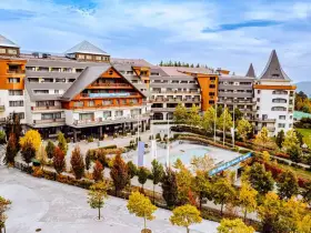 Hotel Gołębiewski w jesiennej odsłonie. Widać jego rozległą architekturę i otoczenie pełne kolorowych drzew.