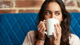 Mujer con taza blanca, quizás probando una bebida sin cafeína para superar la abstinencia de cafeína.