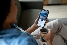 Kobieta sprawdza saldo konta na telefonie, trzymając kubek kawy.