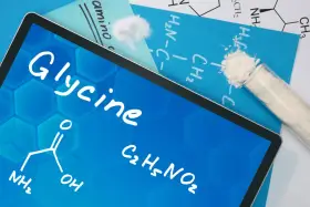 Tablet z napisem "Glycine", wzorem chemicznym i próbówką z proszkiem. Informacje o glicynie i jej dawkowanie.