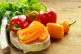 Peperoni piccoli colorati, pronti per gustose ricette. Un coltello e prezzemolo completano la scena.