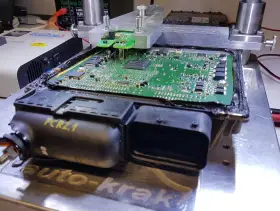 Naprawa sterownika silnika PCR2.1, który powodował wypadanie zapłonu. Widoczna płyta główna z elementami elektronicznymi pod specjalistycznym uchwytem.
