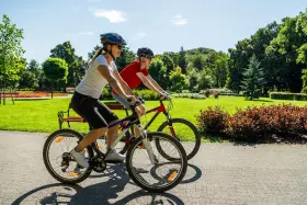 Dwie osoby na rowerach cieszą się pięknym dniem w parku. To pokazuje, co daje jazda na rowerze: radość, aktywność i kontakt z naturą.