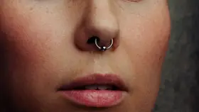 Zbliżenie na twarz z kolczykiem w nosie (septum). Czy septum boli? To pytanie zadaje sobie wiele osób przed piercingiem.