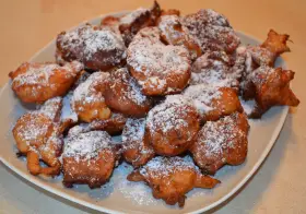 Puszyste paczki z serka homo, posypane cukrem pudrem, kuszą swoim złotym kolorem i apetycznym wyglądem.