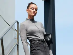 Elegancki strój do pracy w biurze: szary golf, czarne jeansy i torebka. Idealny na co dzień.