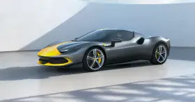 Szary Ferrari 296 GTB z żółtymi pasami na masce i dachu, stojący na betonowej posadzce.