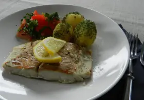 Filet z dorsza z piekarnika w folii, podany z ziemniakami i pomidorami.