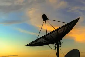 Antenna parabolica in controluce al tramonto, pronta a connettersi al mondo tramite internet satellitare.
