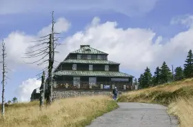 Schronisko Odrodzenie w Karkonoszach, z charakterystyczną architekturą i otoczone suchymi drzewami.