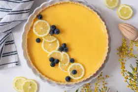Tarta de limón al horno, decorada con rodajas de limón y arándanos. Un postre refrescante y vibrante.