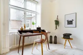 Ett elegant skrivbord i oljad ek med en läderklädd stol. En gammal skrivmaskin står på ett litet sidobord.