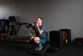 Mężczyzna wykonuje głęboki **squat** z kettlebell w rękach, ćwicząc siłę w siłowni.