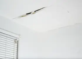 Widoczne pęknięcia na suficie w starym domu, świadczące o jego wieku i potrzebie remontu.