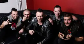 Pięciu mężczyzn w skórzanych kurtkach i z rockowymi fryzurami, jakby gotowi na nocny koncert. Wyglądają jak zespół nocny kochanek.