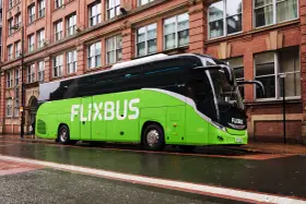 Zielony autokar FlixBus na mokrej ulicy. Wiele osób chwali sobie podróże tymi autobusami, a flixbus opinie są zazwyczaj pozytywne.