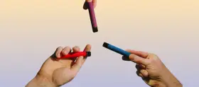 Manos sostienen vapers de colores: rojo, azul y morado. Una opción para un vaper sano.